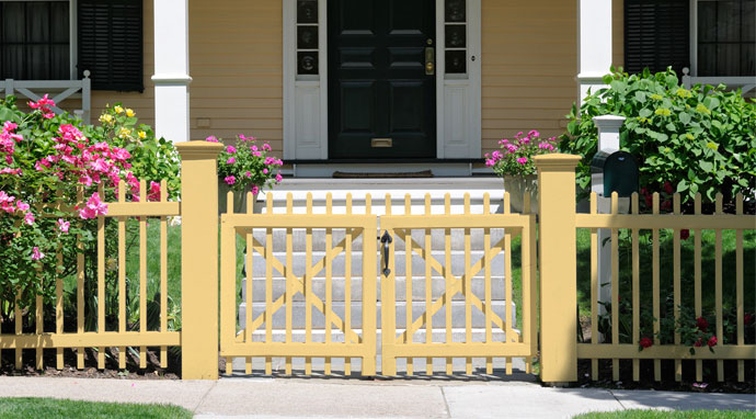 Benjamin Moore&rsquo;s straw (2154-50) paint color on this fence blends well with white trim.