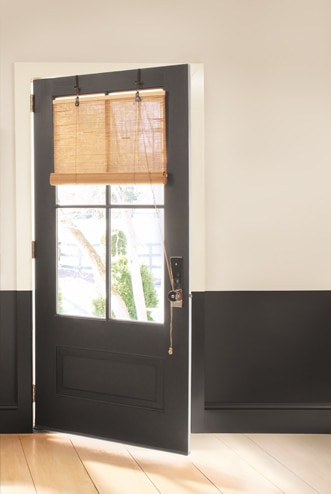 A wall with deep brown paint on the lower half, neutral paint on the upper half, and a matching deep brown door.