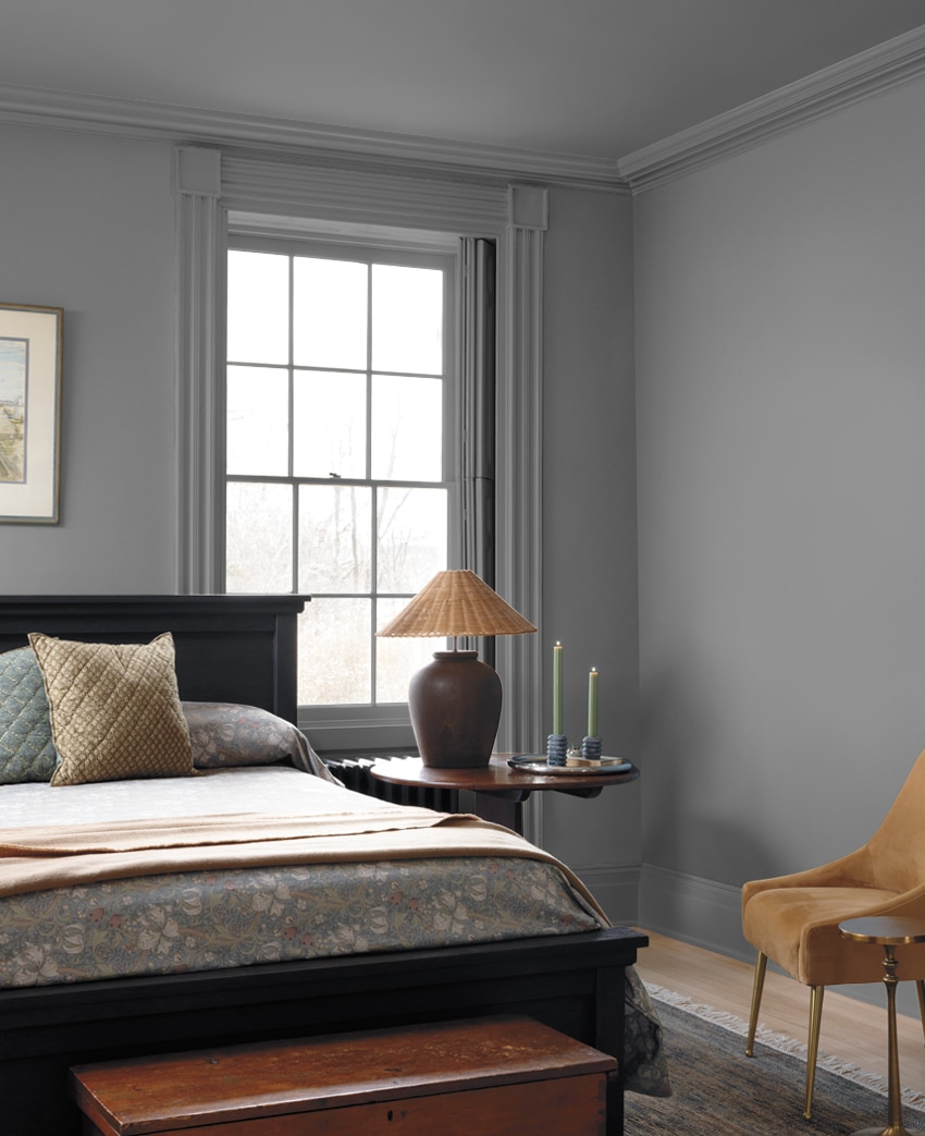 Green walls brighten up a traditional bedroom with patterned linens and a dark area rug.