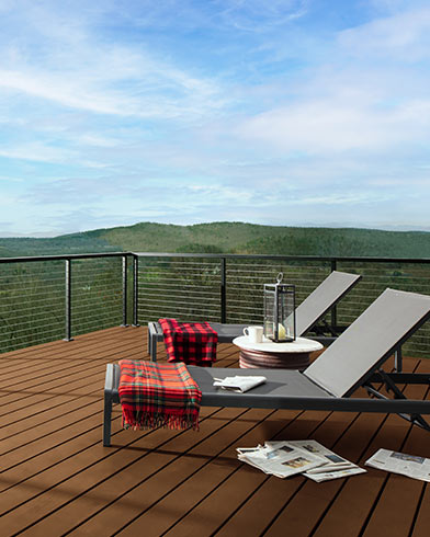 Deux chaises longues pliantes et couvertures rouges sur une grande terrasse enduite de teinture Woodluxe au fini opaque de couleur Ton Cèdre Naturel ES-45.