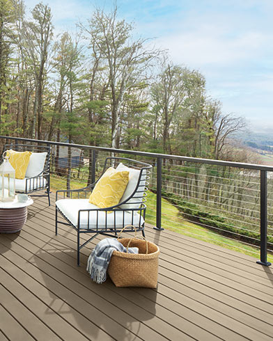 Jolis meubles de jardin rembourrés blancs avec coussins décoratifs jaunes et petite table sur une terrasse enduite de teinture Woodluxe au fini opaque de couleur Gris Beige ES-51.