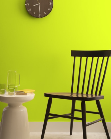 A brown clock hangs on a Snow Cone-painted wall above a dark wood chair and small dining table.