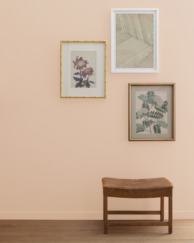 A Nature's Symphony-painted wall with three framed art pieces, a small bench, and a floor lamp.