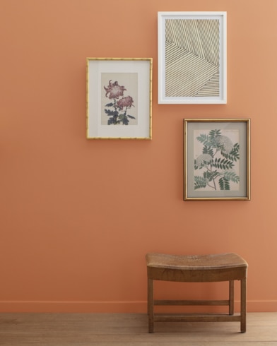 A Firenze-painted wall with three framed art pieces, a small bench, and a floor lamp.
