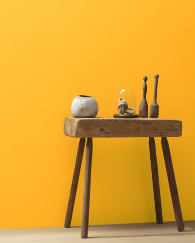 Ceramic artifacts are placed on a modern wooden table in front of a wall painted Citrus Blast.