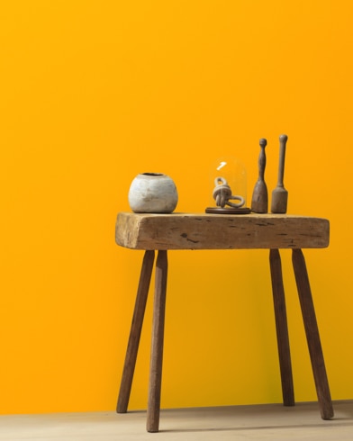 Ceramic artifacts are placed on a modern wooden table in front of a wall painted Mandarin Orange.