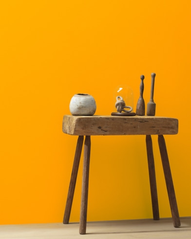 Ceramic artifacts are placed on a modern wooden table in front of a wall painted Orange Sky.