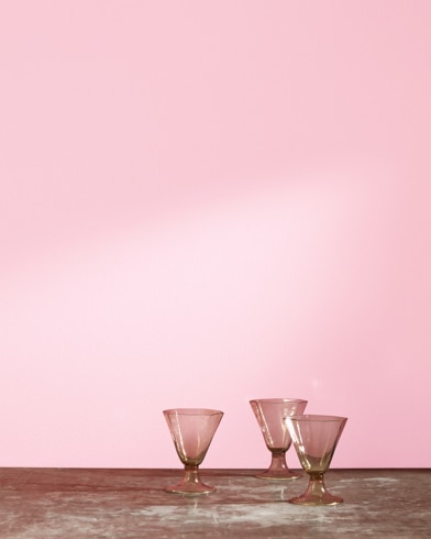 Three glass cups in front of a Country Pink-painted wall.