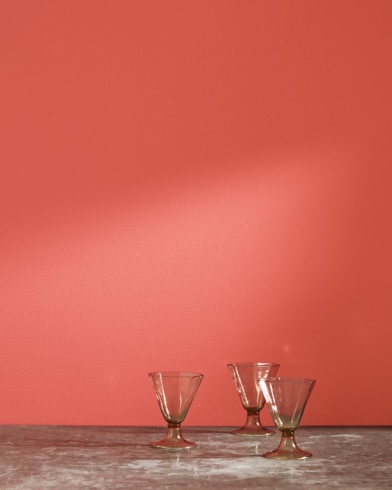 Tres copas de vidrio delante de una pared pintada de color Pimiento Habanero.