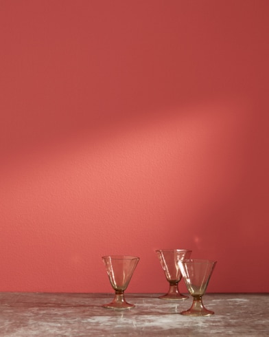 Three glass cups in front of a Red Parrot-painted wall.