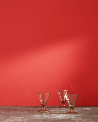 Three glass cups in front of a Ruby Red-painted wall.