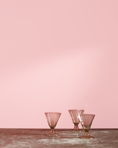 Three glass cups in front of a Smashing Pink-painted wall.
