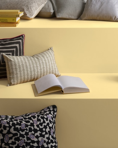 Graphic pillows and stacks of books on a multi-level reading nook painting in Golden Honey.