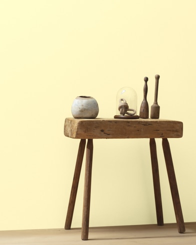 Ceramic artifacts are placed on a modern wooden table in front of a wall painted Provence Cr�me.