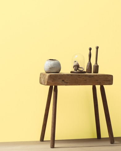 Ceramic artifacts are placed on a modern wooden table in front of a wall painted Yellow Lotus.