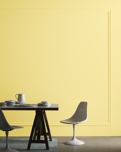 A midcentury modern dining table with two chairs sits in front of a wall painted Copacabana.