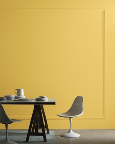 A midcentury modern dining table with two chairs sits in front of a wall painted Showtime.