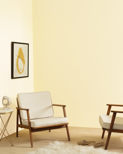 A living room with two chairs, a modern lamp, and shag carpet is painted Windham Cream.