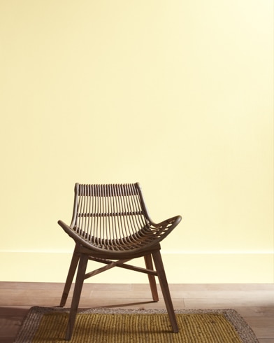 A modern rattan chair with a curved seat sits in front of a Lighting Bolt-painted wall.