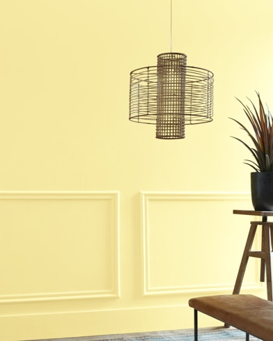 A Sun City-painted living room hosts a wiry light fixture while a wood table and potted plant are just out of focus.