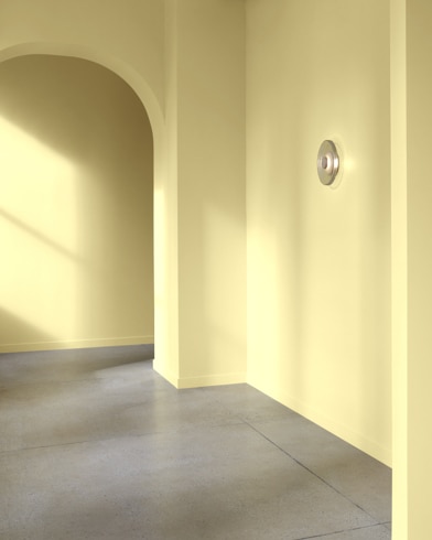 An arched hallway in a modern home is painted Yellow Clover.
