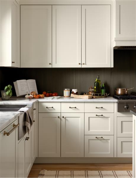 A kitchen with painted cabinets in White Down OC-131 with brass handles. The kitchen features a fluted splashback painted in Durango 2137-30, both part of the Colour Trends 2027 collection.