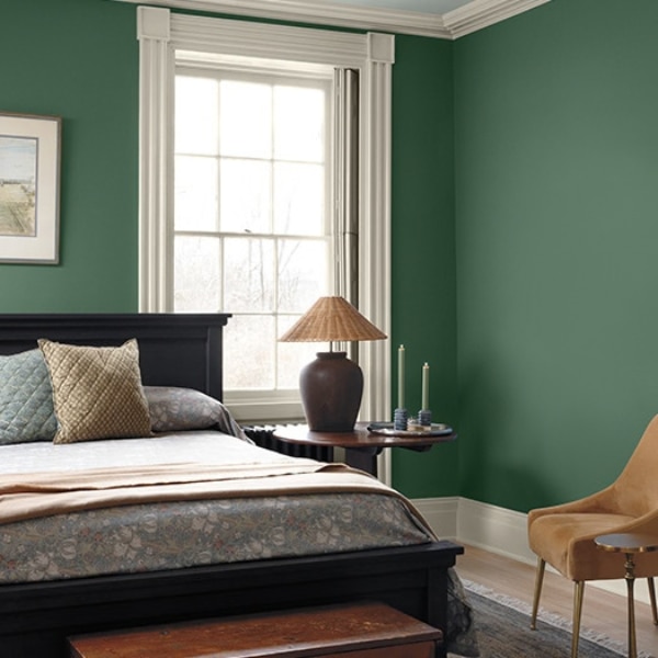 A bedroom scene with walls painted in Benjamin Moore Colour of the Year 2027, Webster Green HC-130. Combined with White Down OC-131 on the woodwork and Nelson Blue CW-635 on the ceiling, part of the Colour Trends 2027 collection.