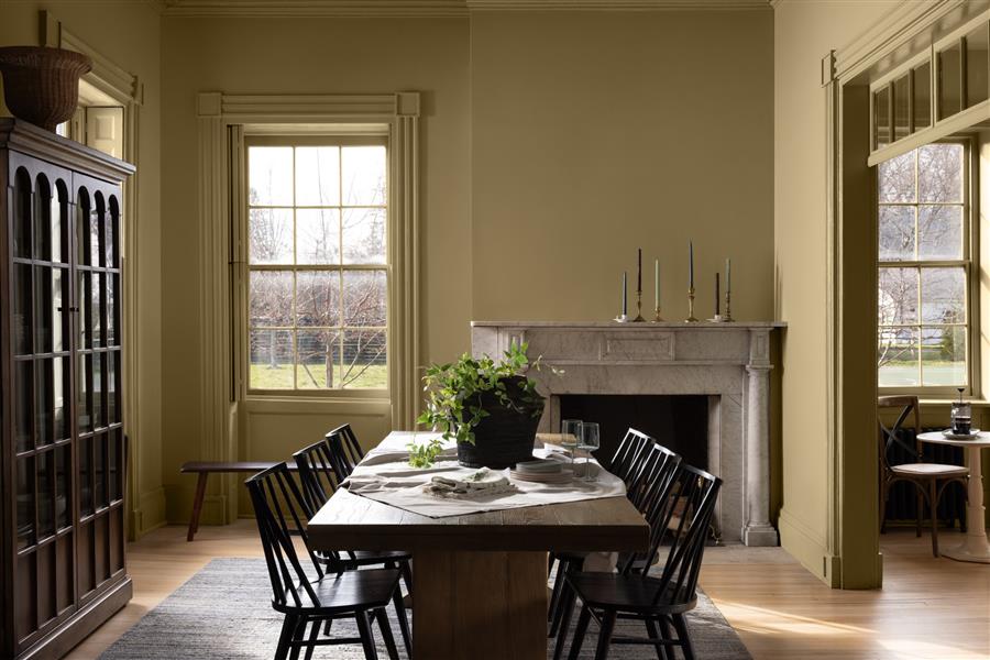 A dining room with a marble fireplace and walls and woodwork colour drenched in Shakespeare Tan 228, part of the Colour Trends 2027 collection.