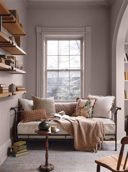 A day bed, dressed with a blanket and reading book, in an alcove that is colour drenched in Wild Aster 1240 from the Benjamin Moore Colour Trends 2027 collection.